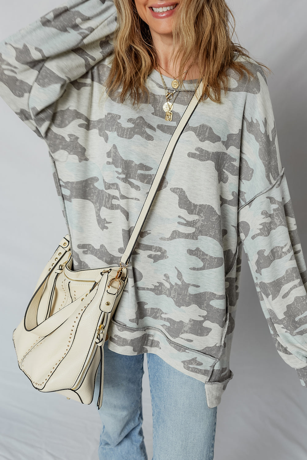 Gray camo oversized sweatshirt, model raising one arm