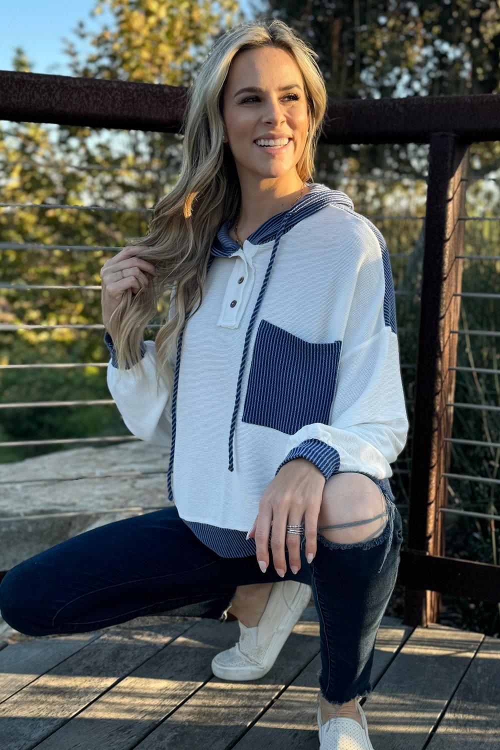 White and blue knit hoodie, model crouching