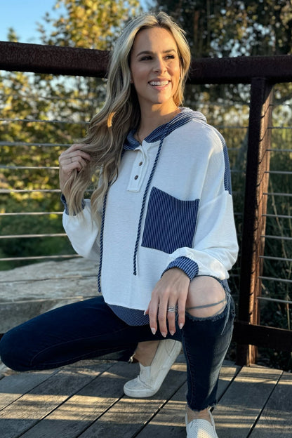 White and blue knit hoodie, model crouching