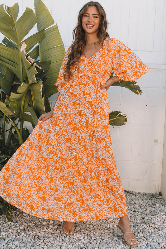 Orange floral maxi dress with flutter sleeves, model swinging the skirt, front view