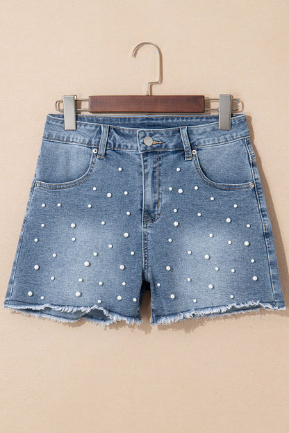 Medium wash denim shorts with scattered pearls on a hanger, front view