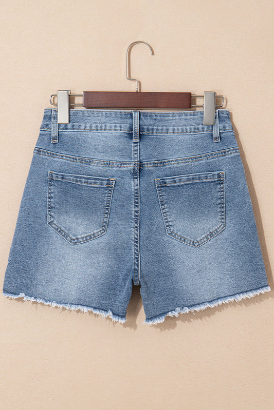 Back of the medium wash pearl denim shorts on a hanger