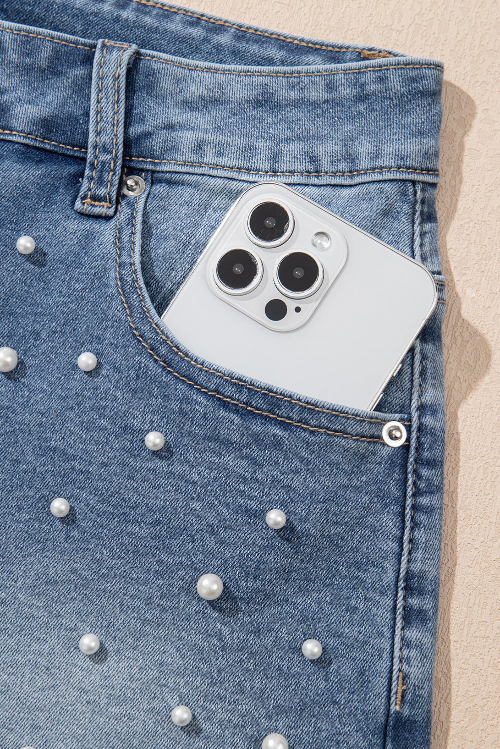 Close-up of the pearl studs and front pocket holding a phone