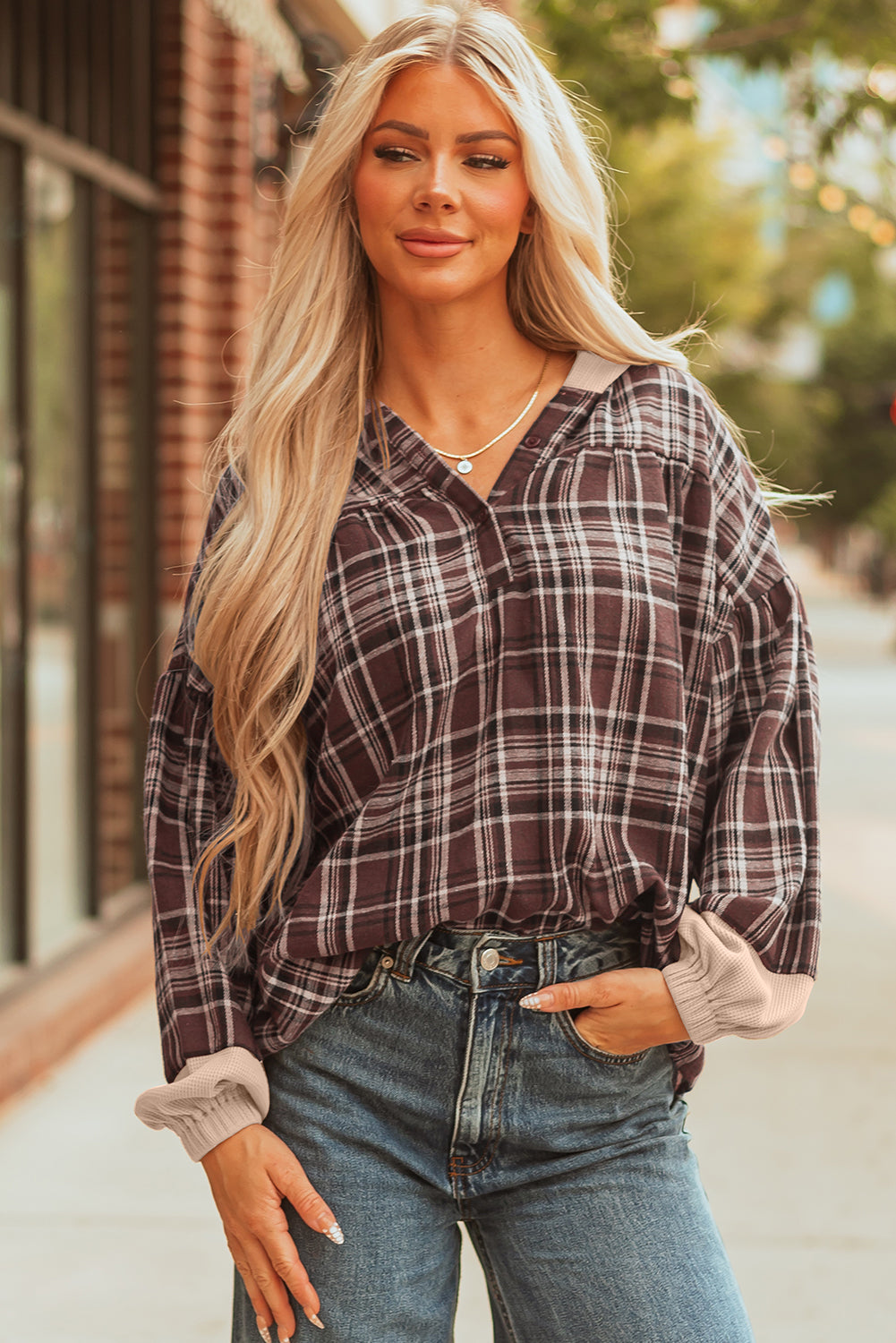 Brown plaid pullover top, model with a hand in her jeans pocket