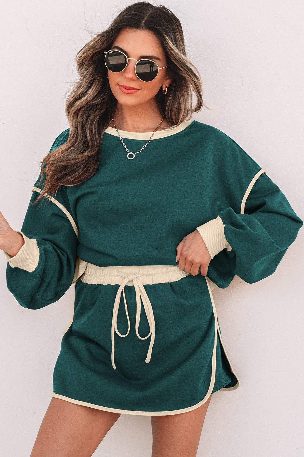 Evergreen pullover and skort set with cream piping, model in sunglasses, front view