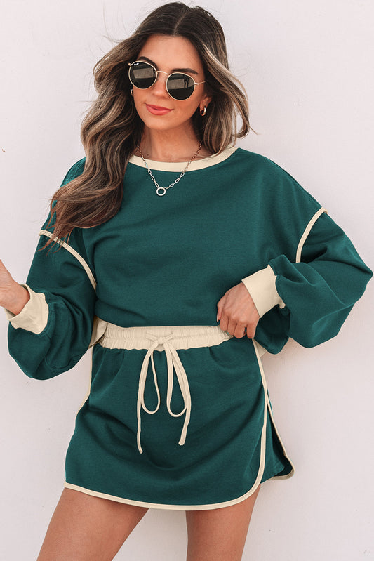 Evergreen pullover and skort set with cream piping, model in sunglasses, front view