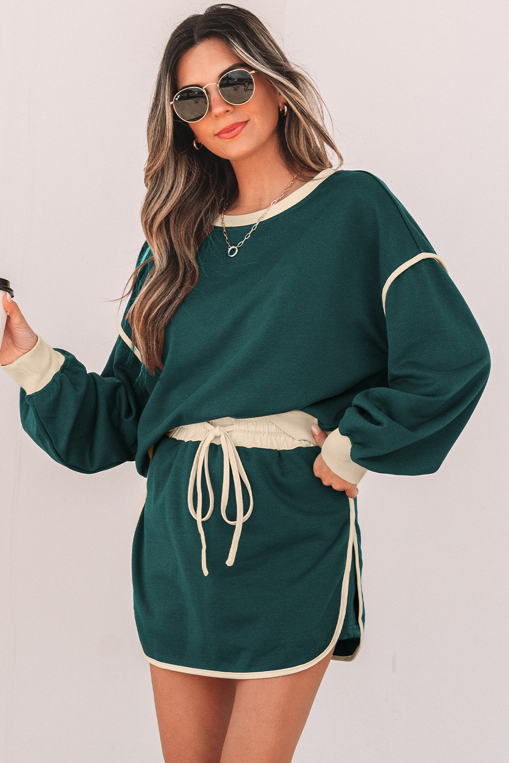 Evergreen skort set worn with sunglasses, model holding a coffee cup