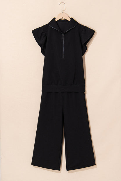 Black quarter-zip top and wide-leg pants on a hanger, front view