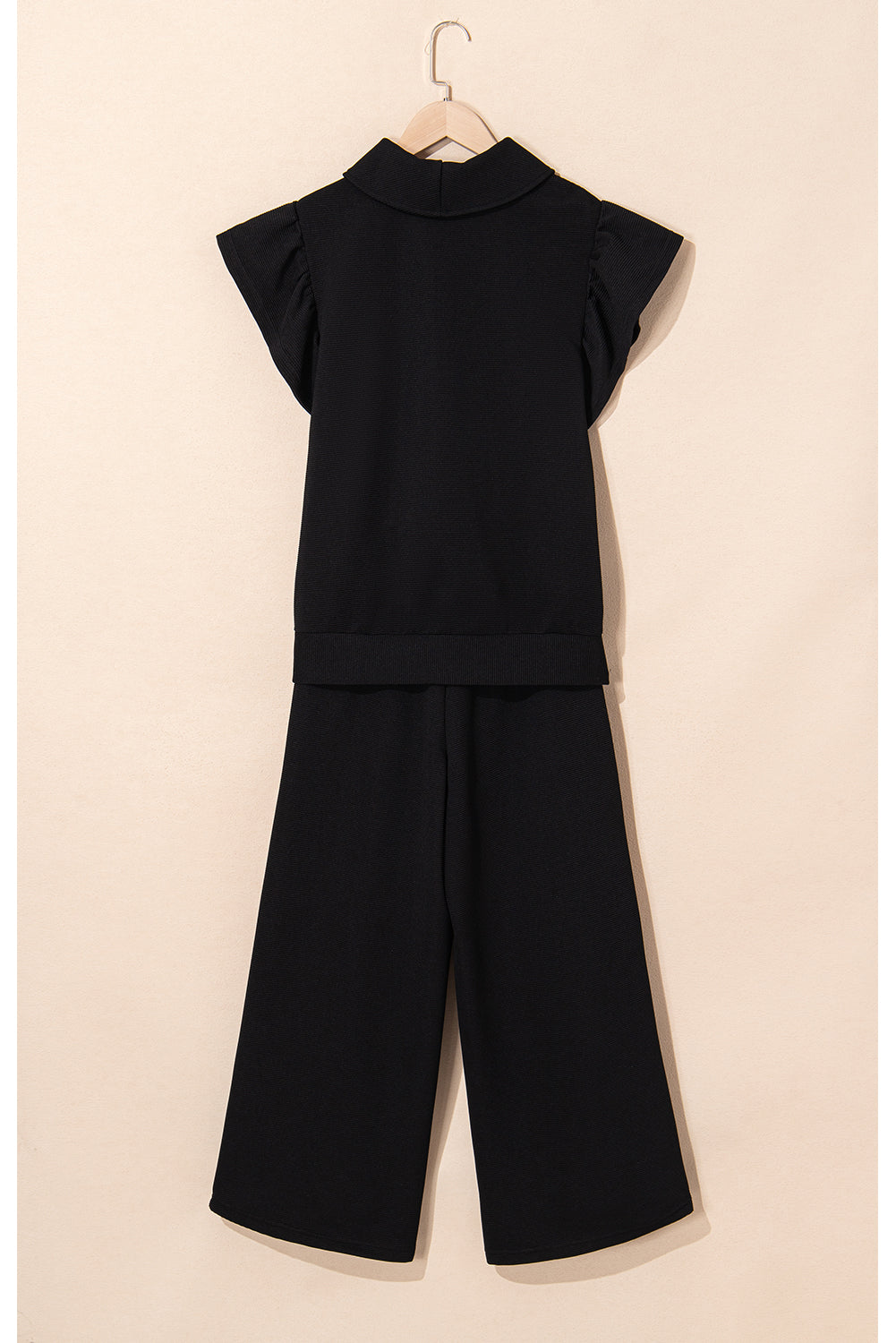 Black quarter-zip top and wide-leg pants on a hanger, back view