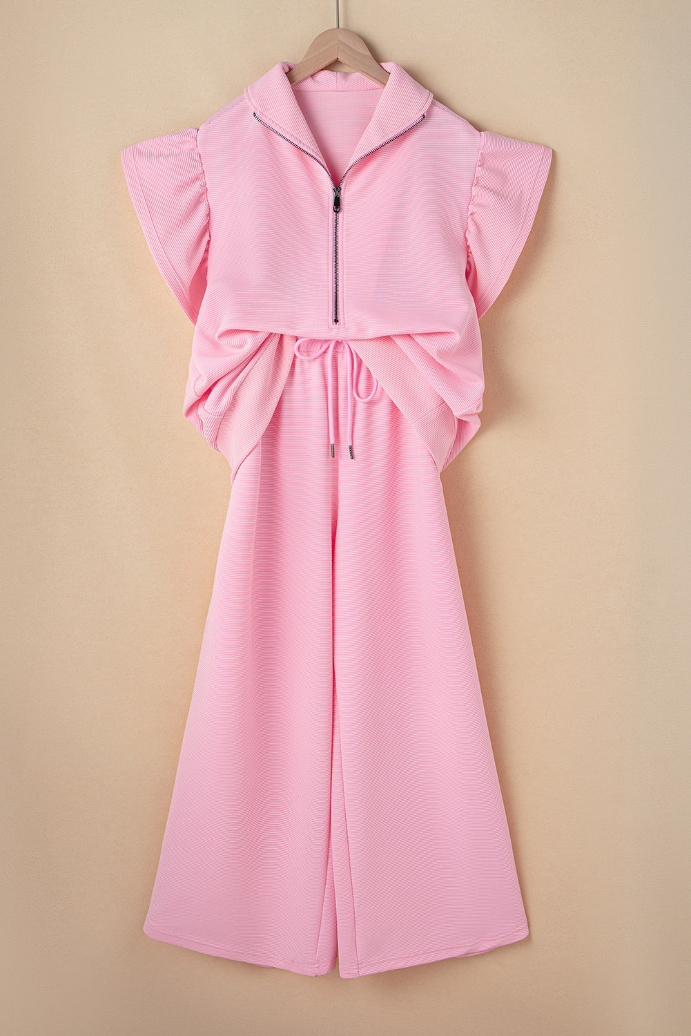 Pink quarter-zip top and wide-leg pants set on a hanger