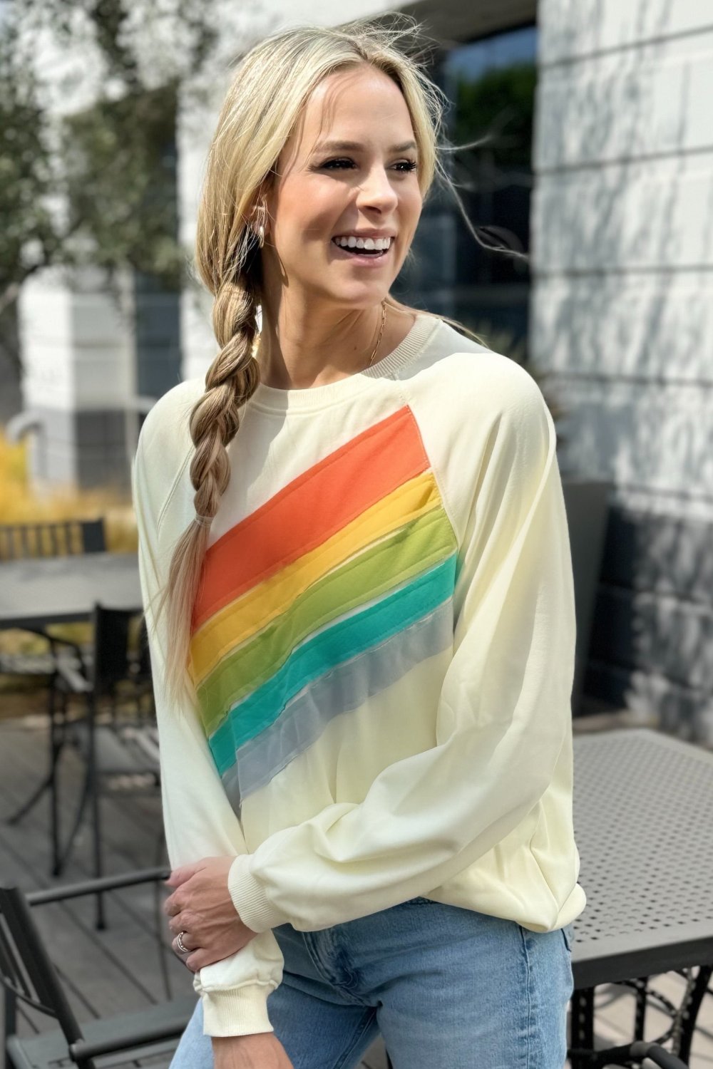 Close front view of the rainbow band on the cream sweatshirt