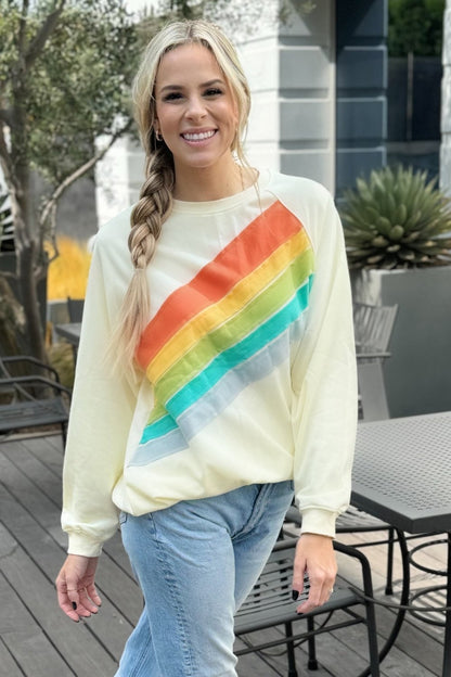 Cream rainbow sweatshirt, model smiling, front view