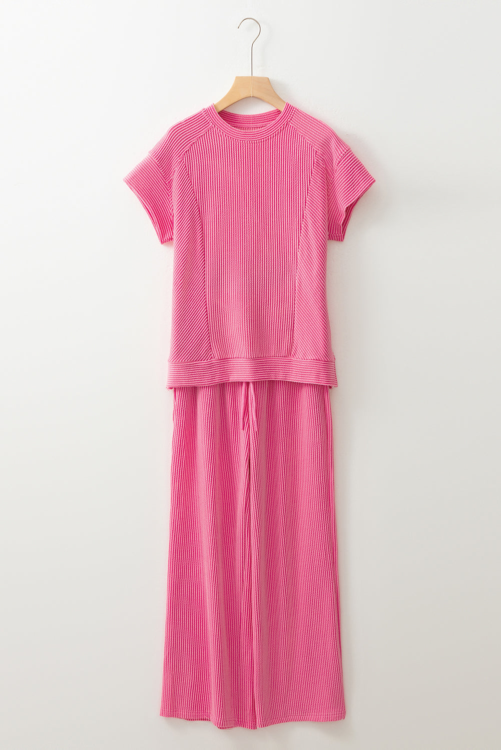 Bright pink ribbed knit tee and wide-leg pants set on a hanger