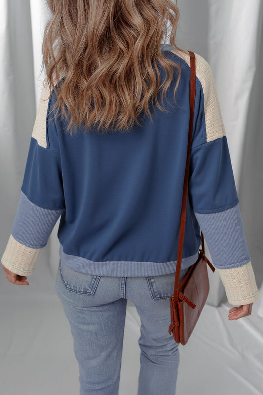 Back of the dark blue color-block knit top with a brown crossbody bag