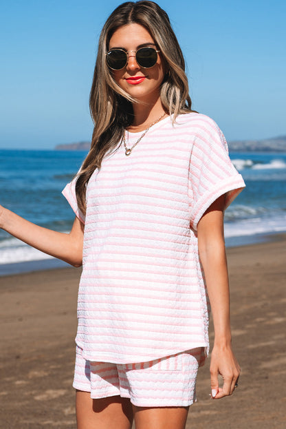 Pink and white striped tee and shorts, front view by the sea