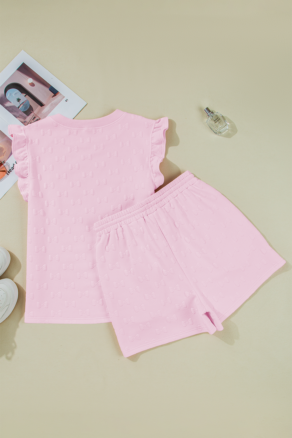 Pink ruffle sleeve top and drawstring shorts laid flat at an angle