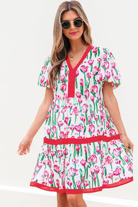 Pink tulip print babydoll dress with red trim, model in sunglasses