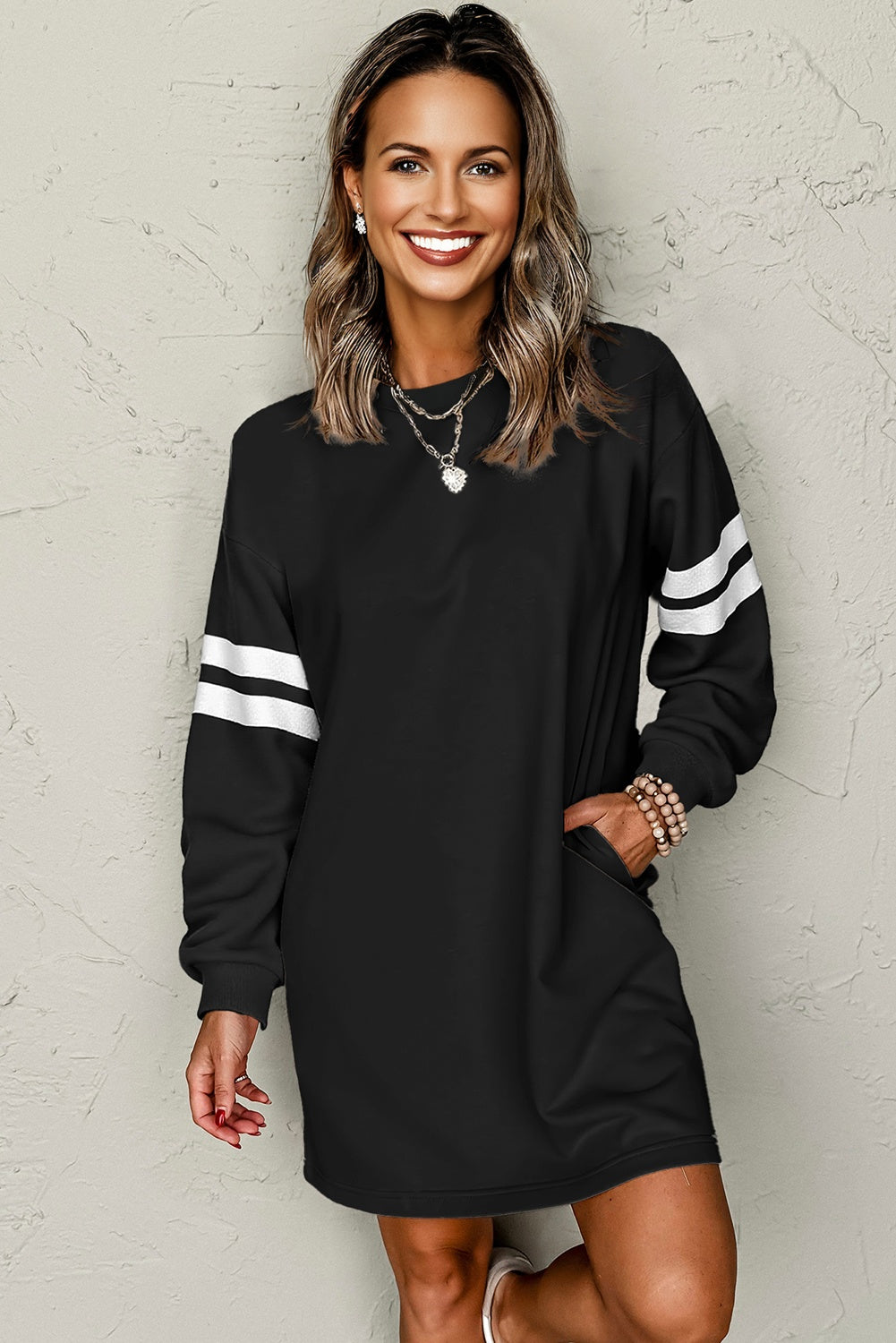 Black varsity sweatshirt dress, model with a hand in the pocket