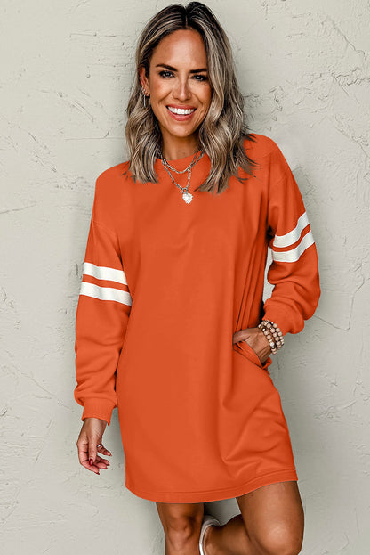 Orange varsity sweatshirt dress, hand in the side pocket